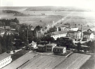 Stadsvy över ett antal större byggnader utmed vattendrag
