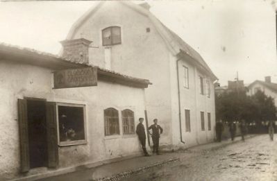 Gatuvy med 2 pojkar stående vid envåningshus
Nyckelord: Affärsskylt