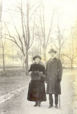 Man och kvinna stående på gångväg intill vattendrag
Nyckelord: Dräkt Muff Käpp