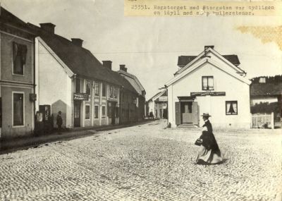 Kvinna gående över kullerstensbelagt torg
Nyckelord: Kullersten Dräkt Affärsskylt