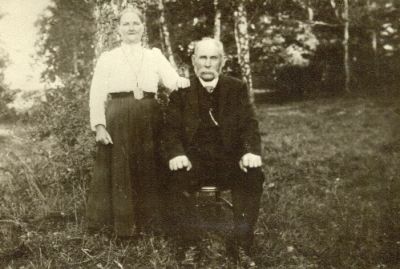 Stående kvinna och sittande man i skogsbacke
Nyckelord: Dräkt Klockkedja