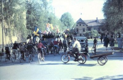 Lövklädd vagn med ungdomar 
Nyckelord: Realexamen Balong Flagga Moped Cykel Bil 