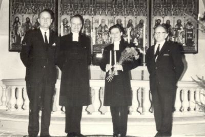 4 män varav 2 prästklädda i kyrkorum
