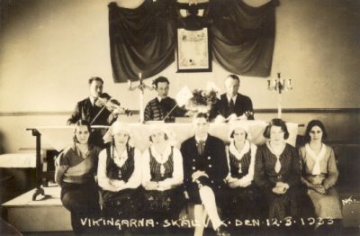 Män och kvinnor med musikinstrument i lokal
Nyckelord: Dräkt