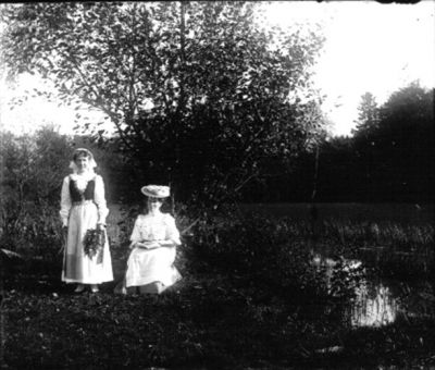 2 kvinnor vid vattendrag
Nyckelord: Dräkt Hatt