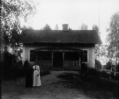 2 kvinnor framför hus
Nyckelord: Dräkt
