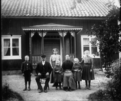 Man kvinna och 5 barn framför hus
Nyckelord: Dräkt Klockkeja Snickarglädje