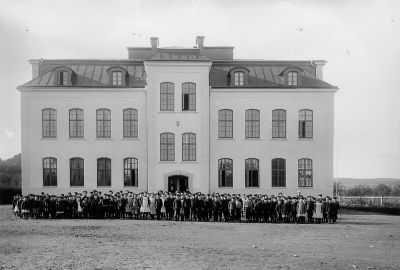 Elever framför skolbyggnad
