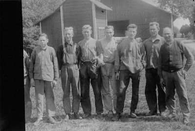 7 män framför byggnad
