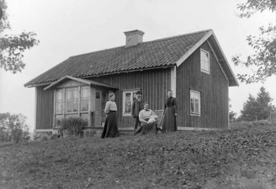 1 man 3 kvinnor och 1 barn framför byggnad
