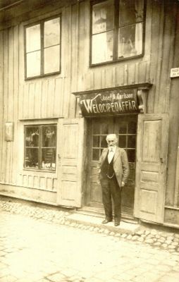 Man i dörröppning till velocipedaffär
Nyckelord: Velociped