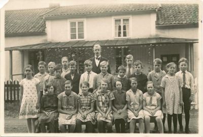 Elever med lärare framför skola
