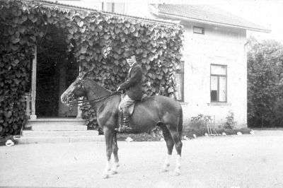Man till häst framför byggnad
Nyckelord: Häst