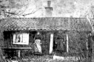 1 man och 2 kvinnor framför liten stuga
