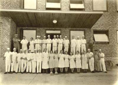 Män och kvinnor framför fabriksbyggnad
Nyckelord: Mjölk;Mejeri:Dräkt