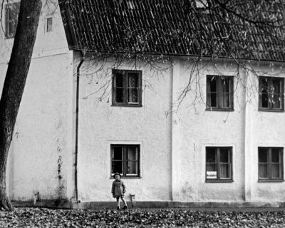 Barn stående vid husvägg
