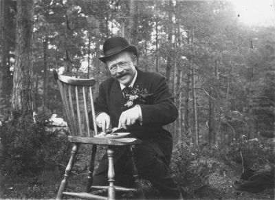 Man med stol som bord i skogen
