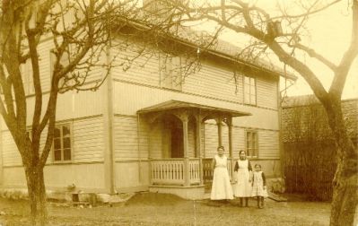 Tre personer framför byggnad
