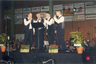 Sångkvartett på scen i sporthall
