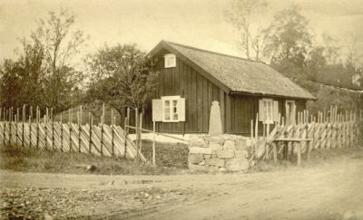 Torpstuga omgiven av gärdesgård

