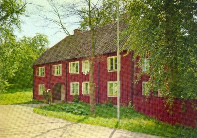 Stor rödfärgad träbyggnad vid väg
