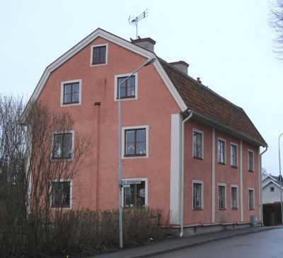 Rosa putsad byggnad med brutet tak
