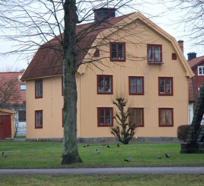 Beige 3-vånings trähusi parkområde
