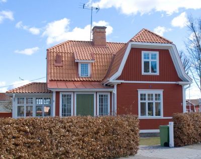 Rött hus med vita knutar och brutet tak
