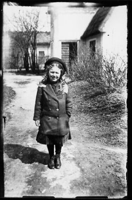 Flicka stående på gång framför byggnad.
