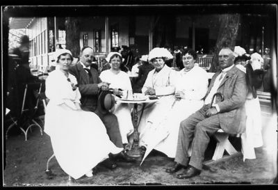 2 män och 4 kvinnor sittande vid kaffebord i park.
Nyckelord: Kaffe