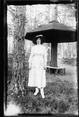 Kvinna stående vid träd framför regnskydd.
