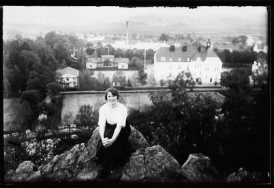 Kvinna sittande på berg med byggnader i bakgrunden.
Nyckelord: Utsikt