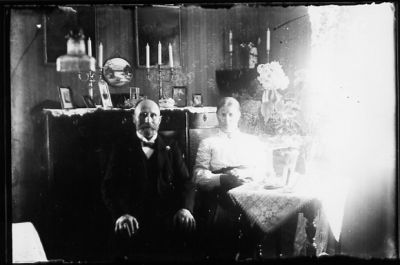 Man och kvinna sittande i rum.
Nyckelord: Byrå Ljusstake Tavla