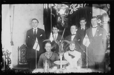 5 män stående och 2 kvinnor sittande vid kaffebord.
Nyckelord: Flagga Kaffe