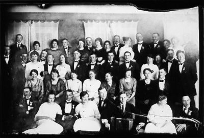 Ett antal personer stående eller sittande i rum.
