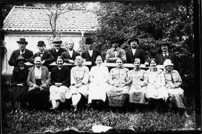 8 män stående bakom bänk där 9 kvinnor sitter.
