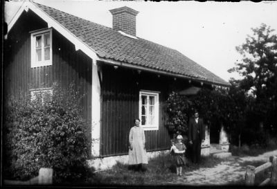 Kvinna och flicka stående framför byggnad.
