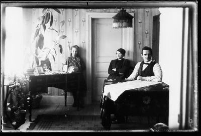 Man och kvinna sittande och flicka stående i rum.
Nyckelord: Skrivbord Lampa