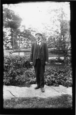 Man stående i trädgård.
