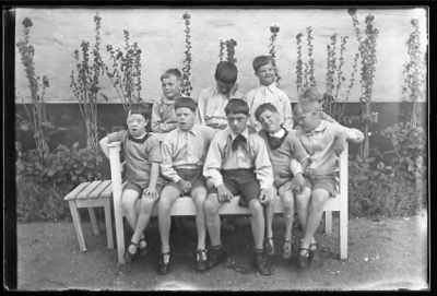 5 pojkar sittande på bänk och 4 pojkar stående bakom.
