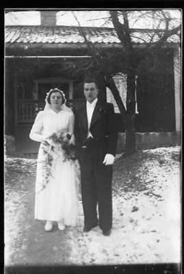 Brudpar stående framför byggnad.
Nyckelord: Vinter