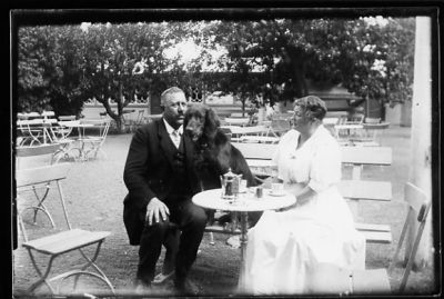 Man, Kvinna och hund sittande i servering utomhus.
Nyckelord: Hund Trädgårdsmöbler Kaffe