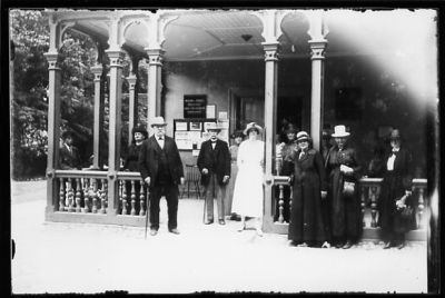 Ett antal män och kvinnor stående framför och på veranda.
Nyckelord: Hotell