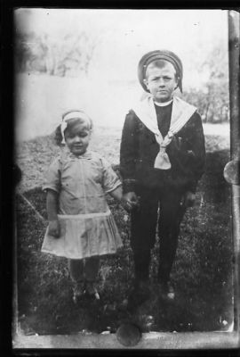 Pojke och flicka stående i gräset.
