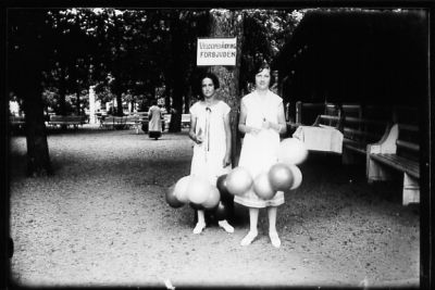 2 kvinnor med ballonger stående vid träd i park.
Nyckelord: Ballong Park