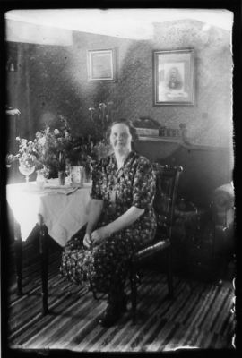 Kvinna sittande i rum.
Nyckelord: Blommor Tavla