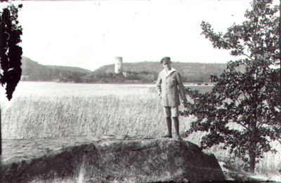 Man stående på sten med vatten och ruin i bakgrunden.
Nyckelord: Vass