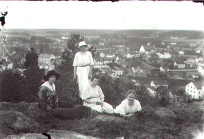 3 sitttande och 1 stående kvinna på berg med stadsvy i bakgrunden.
Nyckelord: Stadsvy Utsikt