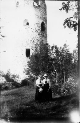 2 kvinnor stående framför ruin.
