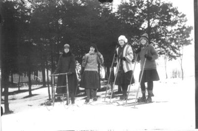3 kvinnor stående på skidor och 1 på spark i skogsbacke.
Nyckelord: Spark Skidor Vinter